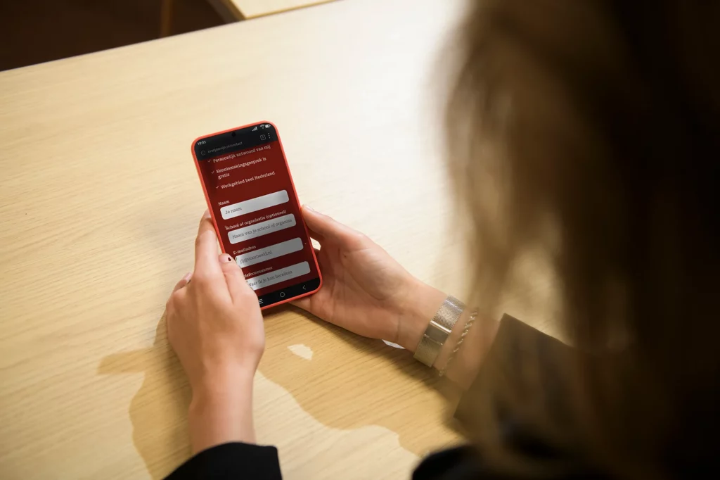 Deelnemer bekijkt de contactpagina op haar telefoon